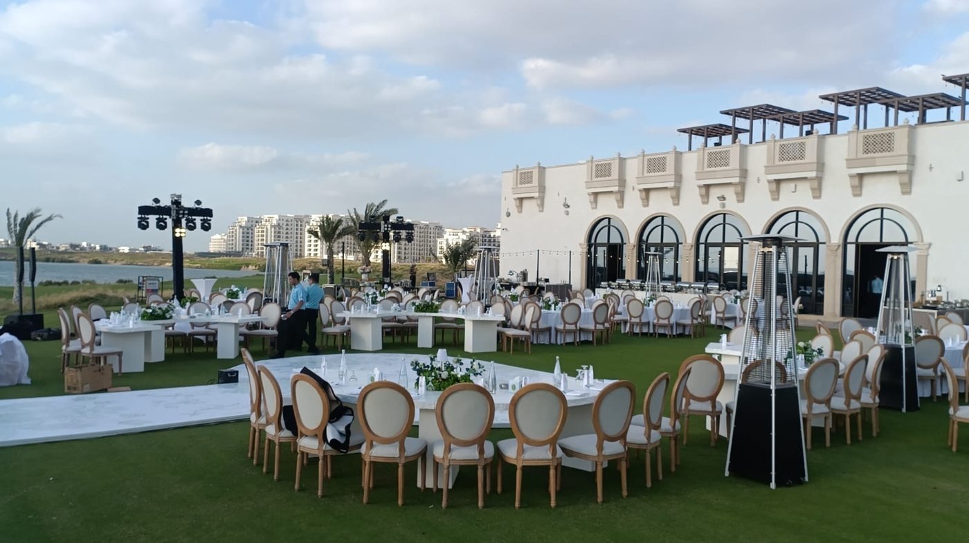 Outdoor lawn setup with round tables and Louis chairs