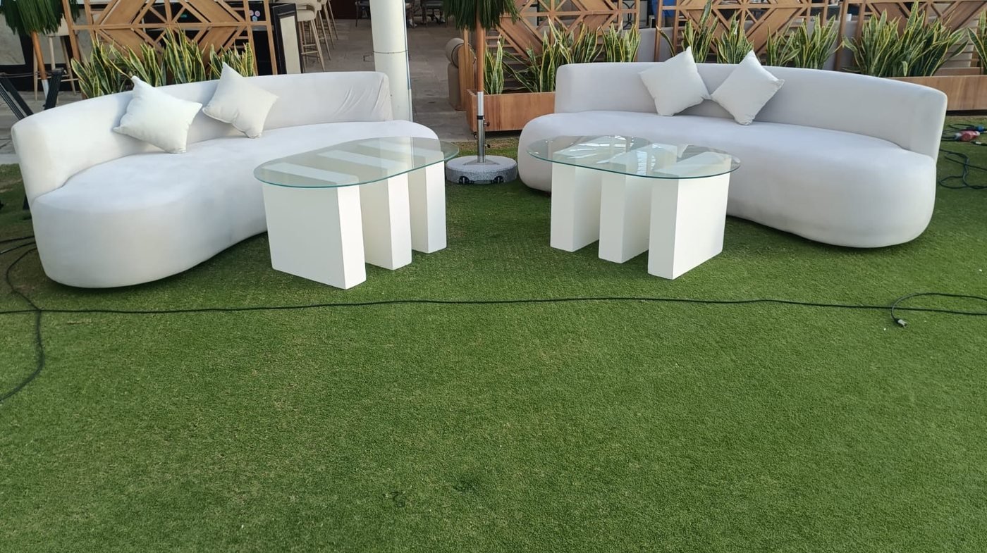 White lounge sofas with glass coffee tables on grass